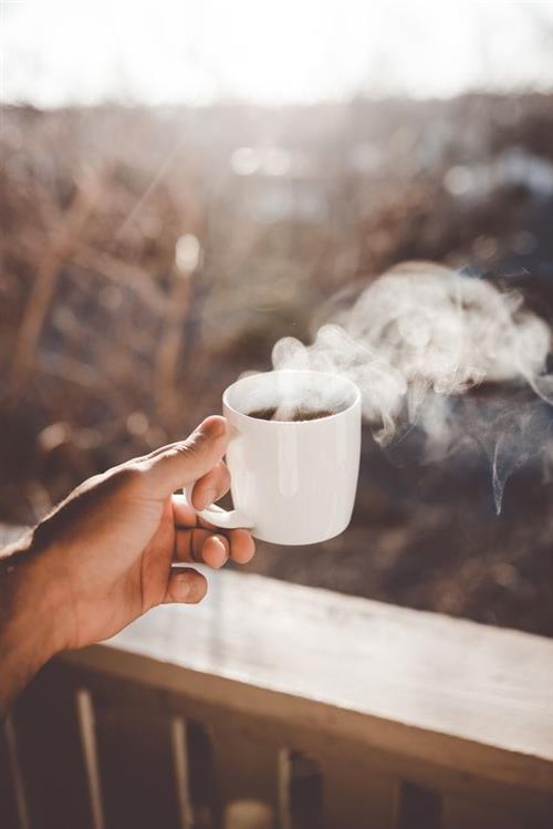 person holding hot coffee cup outside